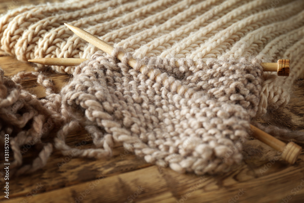 Knitting yarn and needles on wooden background, closeup