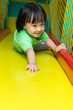 Leinwandbild Motiv Happy Asian Chinese little girl playing slide at indoor playgrou