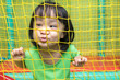 Leinwandbild Motiv Happy Asian Chinese little girl playing behind the net