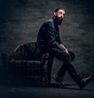 © Fxquadro - Tattooed bearded male sits on a chair.