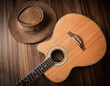 © pondpony - Acoustic guitar and leather cowboy hat laid on wooden floor background,low key.
