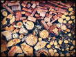 Chopped firewood logs stacked neatly in a wall closeup. Image has vintage filter applied