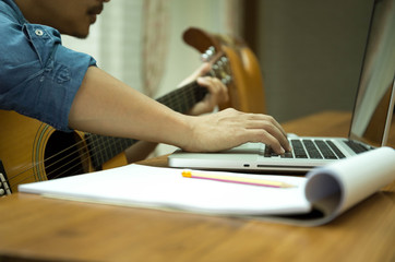 man practicing play the guitar with laptop
