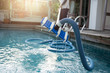 © bignai - Man cleaning swimming pool with vacuum tube cleaner