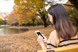 © leungchopan - Asian woman using mobile phone at autumn season