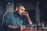 Fototapeta  - Handsome man eating and speaking on mobile phone at the restaurant
