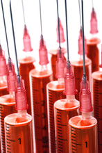 Rows Of 5 Ml Standing Red Medical Syringes. All Syringes Needles Without Caps. Light Shadows. White Background. Vertical.
