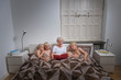 © Connect Images - Grandmother in bed with grandsons reading story book