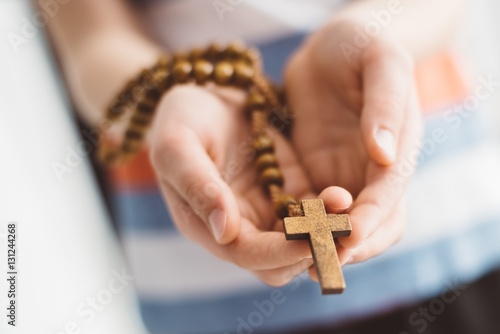 Cuadros en Lienzo Little boy child praying and holding wooden rosary.