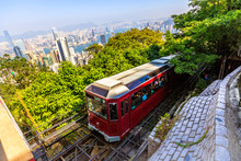 The Popular Red Peak Tram As He Arrives At The Terminus Of Victoria Peak, The Highest Peak Of Hong Kong Island, With Panoramic City Skyline In Background. Sunny Day.