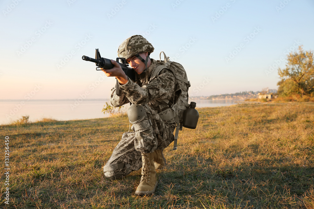 Soldier in camouflage taking aim at military firing range