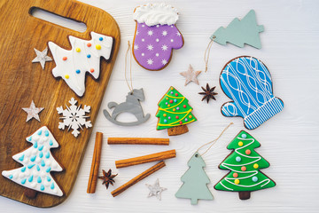  Celebrating New Year at home. Christmas ginger and honey cookies, spices and beads on white wooden table. Fir tree, glove, snowflake, horse shape. Festive bakery top view. Gingerbread with copy space.