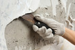 hand removing wallpaper from wall with spatula