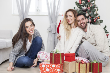 Wall Mural - Friends sitting next to Christmas tree with presents