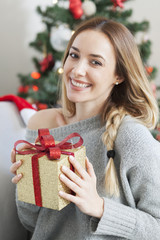 Wall Mural - Beautiful woman with christmas box gift in front of Christmas tree