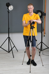 Handsome photographer with camera at working, on photo studio background