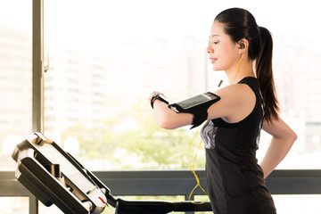 Wall Mural - Beautiful asian woman running treadmill use smartwatch listening