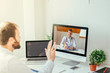 © GENETTICA - Man sitting on desk videoconferencing with doctor on computer at home.