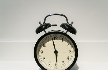 face of Black alarm clock on white shelf with copy space.