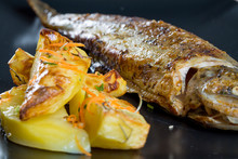 Close Up Of Fresh Fried Trout With Rustic Potatoes On A Black Pl