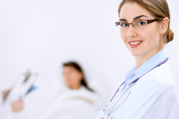 Wall Mural - Female doctor smiling on the background with patient and his doctor