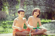 © Jasmin Merdan - Cute little boys on summer meadow splashing water having fun and