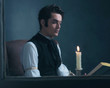 © ysbrandcosijn - Retro victorian man reading book by candlelight sitting by windo