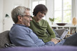 © Westend61 - Smiling mature couple at home on the sofa sharing tablet