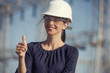 woman electrical engineer is giving thumbs up in front of power lines