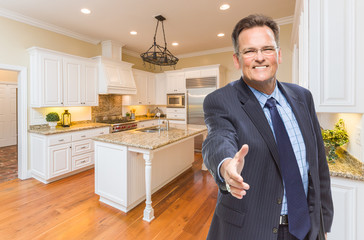 Wall Mural - Smiling Male Agent Reaching for Hand Shake in Beautiful New Kitchen.