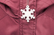 Cute white safety reflector in the form of snowflakes on the winter jacket. Necessary equipment to pedestrians for walks during dark conditions.