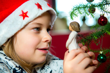 Wall Mural - girl with Santa- cap and wooden angel