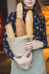 woman holding baguettes of bread in his hand