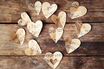 Wall Mural - Paper hearts with music notes on wooden background