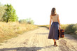 © Africa Studio - Young woman with suitcase walking along countryside road