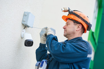 Technician worker installing video surveillance camera on wall