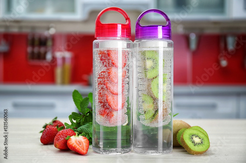 Fotografia, Obraz Bottles with fruit-infused water on kitchen table