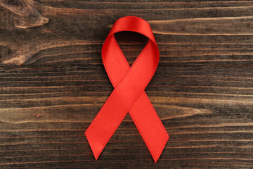 Wall Mural - Red ribbon on wooden background. Aids concept