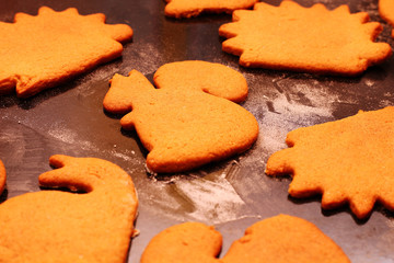 Hot tasty ginger cookies in the shape of various animals on a baking sheet