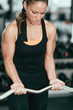 © Microgen - Gym. Woman exercising in gym with barbell weights