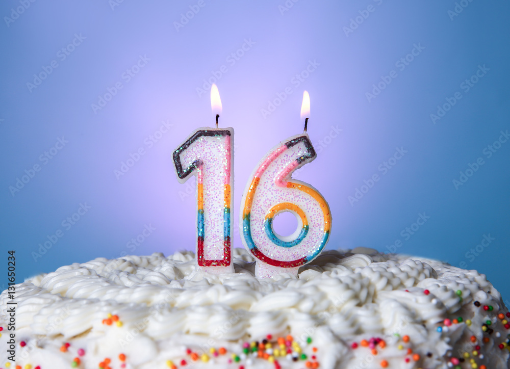 Tasty cake with candles for sixteenth birthday on blue background