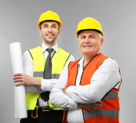 Wall Mural - Handsome engineer and senior worker on light background