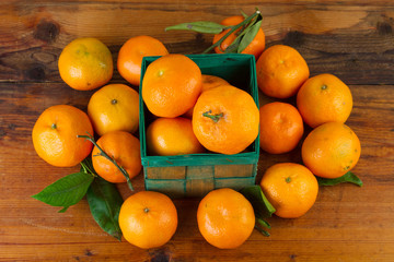 Wall Mural - tangerine orange fruits in green box on old wooden background top view