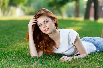 red-haired woman lying in the park on the grass