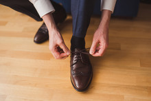 Fashion For Men. Close-up Of A Man Tie The Shoelaces Of His Brown Leather Shoes