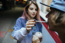 Teenage Girl Feeding Guy With Ice Cream Outdoors