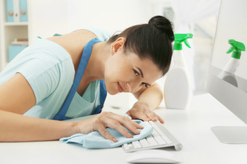 Wall Mural - Young woman cleaning keyboard in office