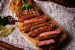 Single roasted medium rare sliced flank beef piece with herbs over wooden bord