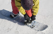 The athlete checks fastenings on a snowboard before descent.