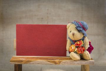 Wall Mural - Little teddy bear with valentine red paper card on wooden chair